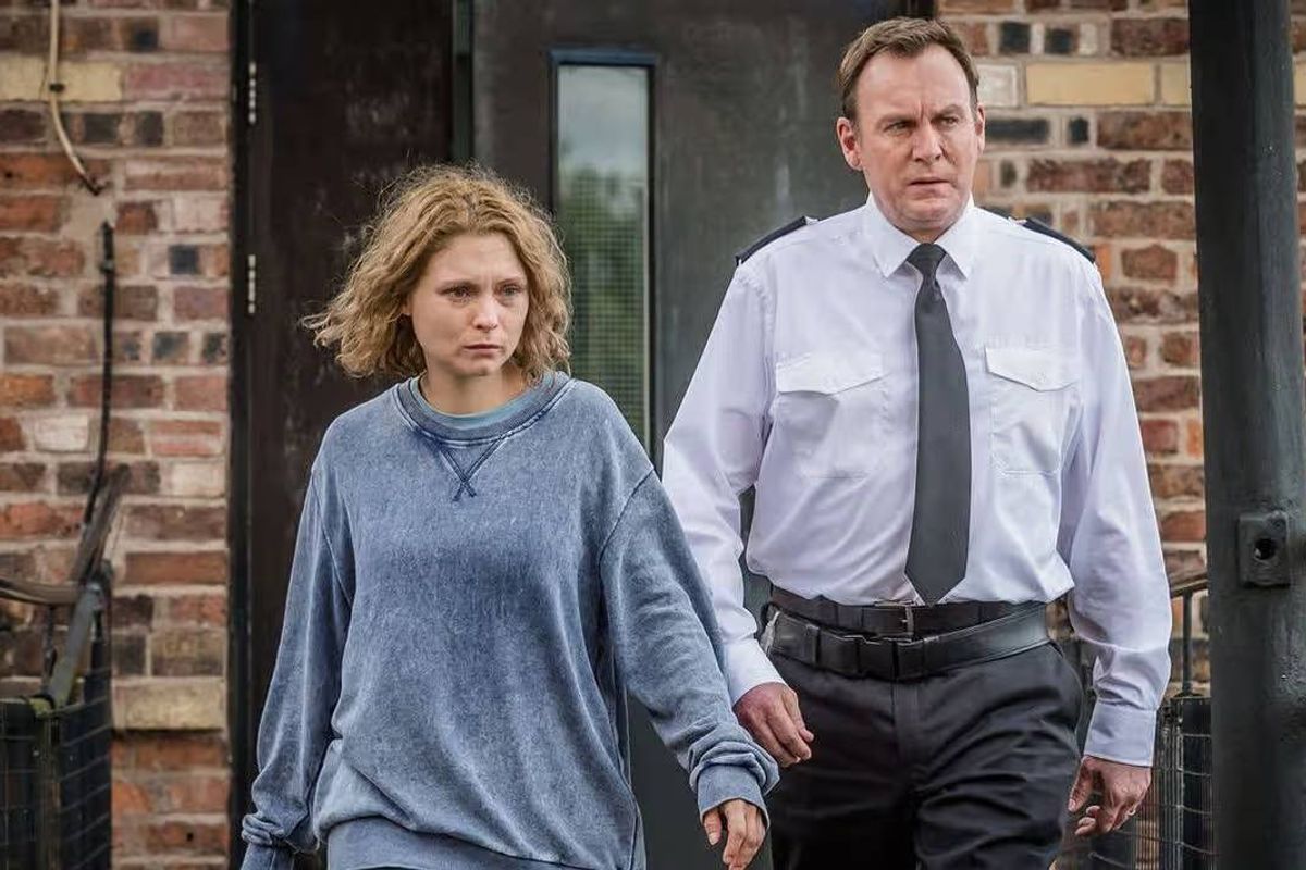 A prison officer and a woman walking.