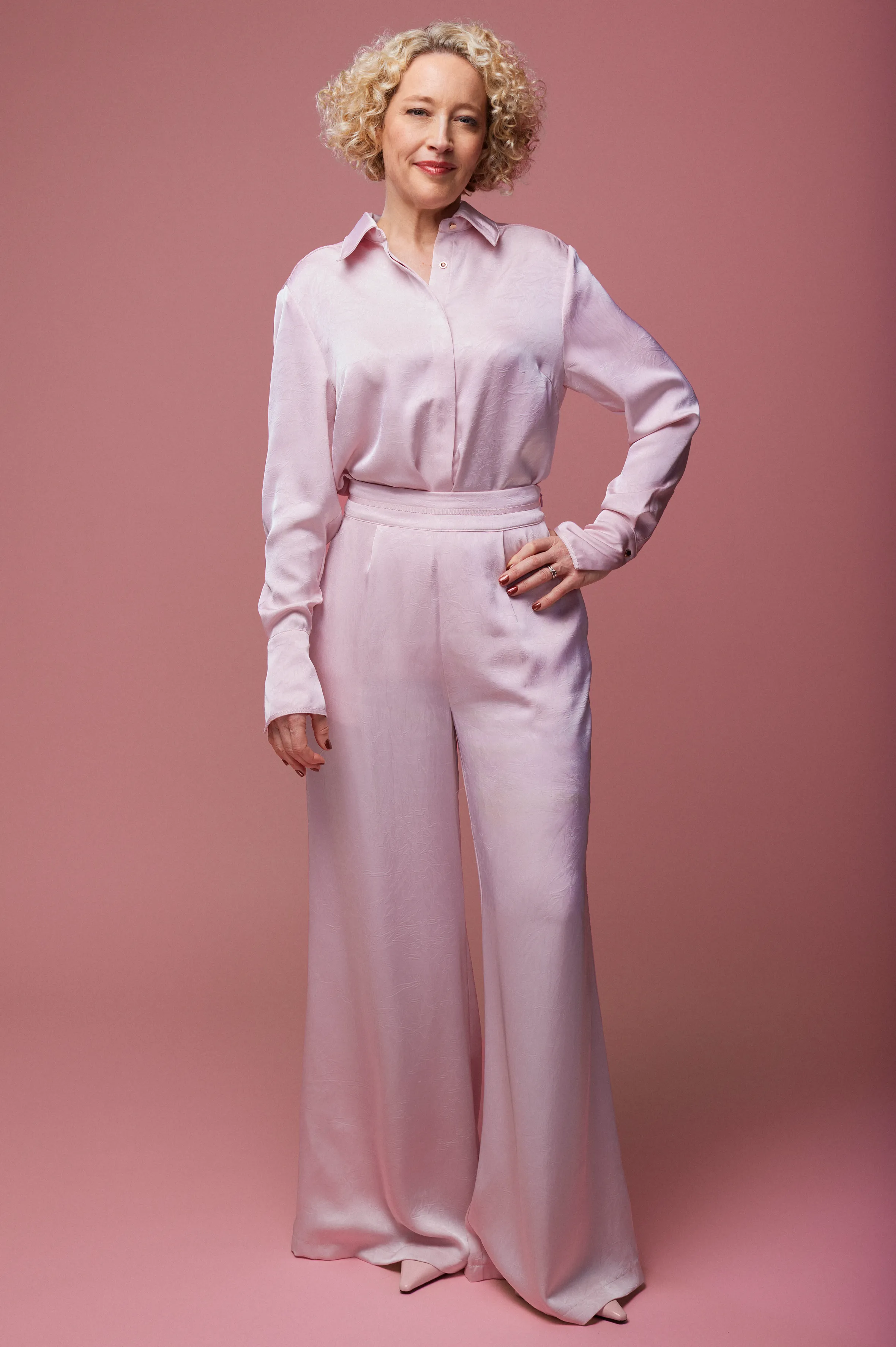 Cathy Newman smiling in a pink satin pantsuit.