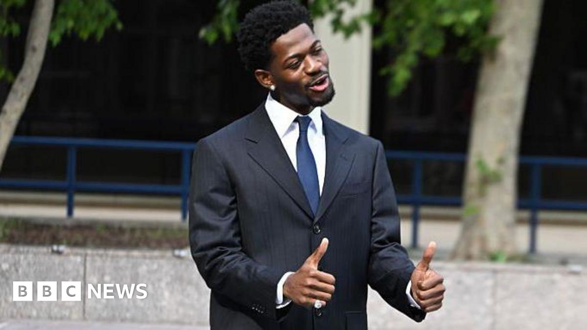 Hill flashed thumbs up to reporters after the hearing. Nas X wearing a suit and with his thumbs up and smiling