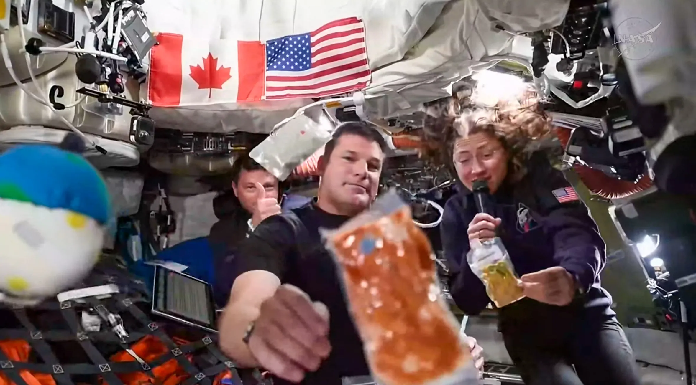 Astronauts Reid Wiseman, Jeremy Hansen, and Christina Koch demonstrate space food inside the Orion spacecraft.
