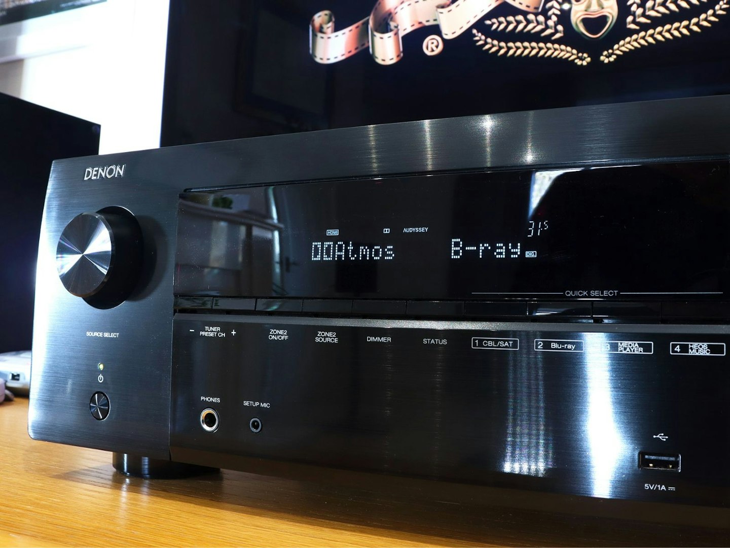 Denon AVR-X2800H Home Cinema Amplifier with dolby atmos display on a stand in front of a TV