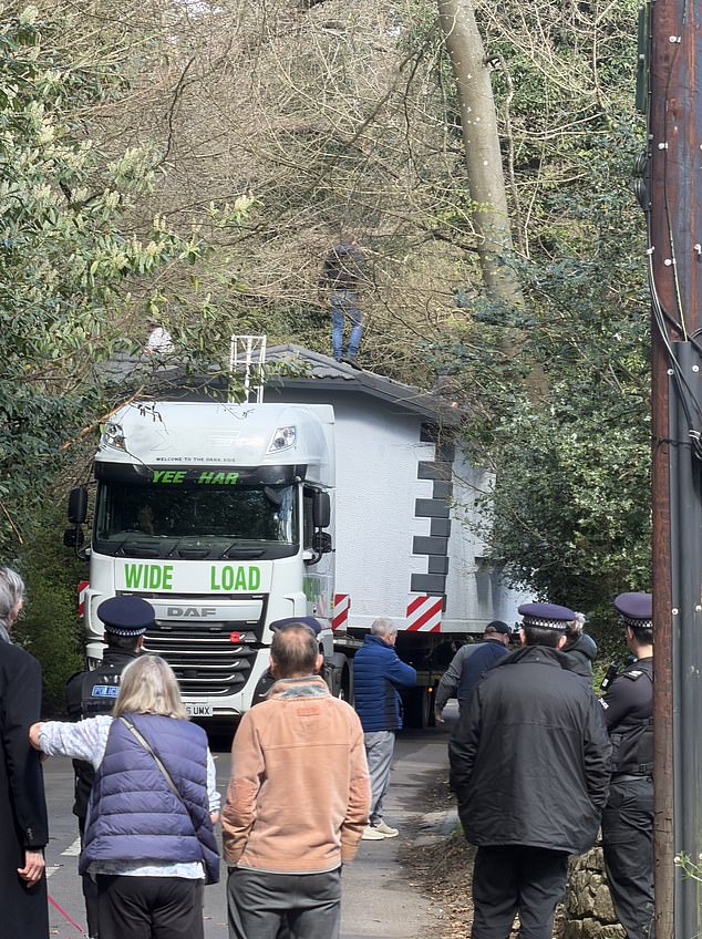 Locals in the Kent village look on as a truck carrying the travellers' home gets wedged in the Kent lane leading to the site