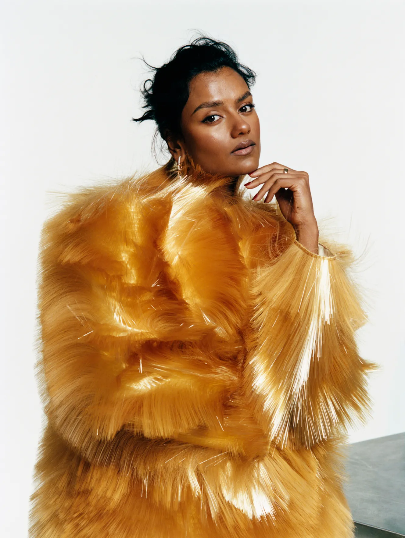 British actress Simone Ashley wearing a dramatic golden fur-like coat.
