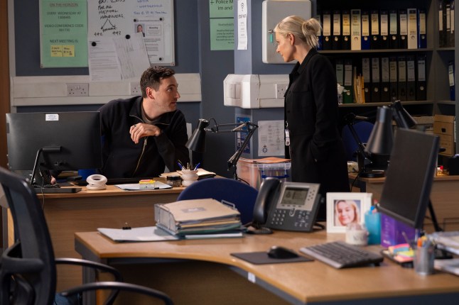 Kit sits at his desk, arguing with Lisa in the police station