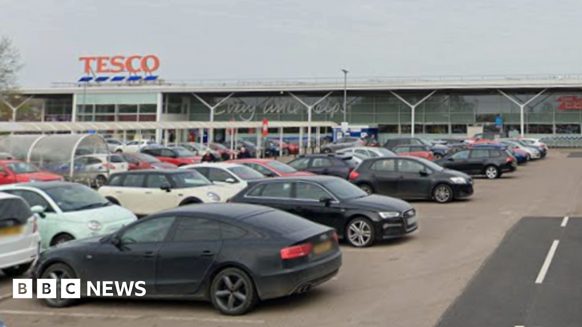 Cars parked in a Tesco car park. The entrance to the store is in the background.