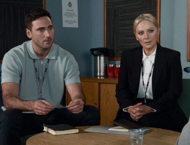 Kit Green and Lisa Swain listening as they talk to someone in the police station in Coronation Street.