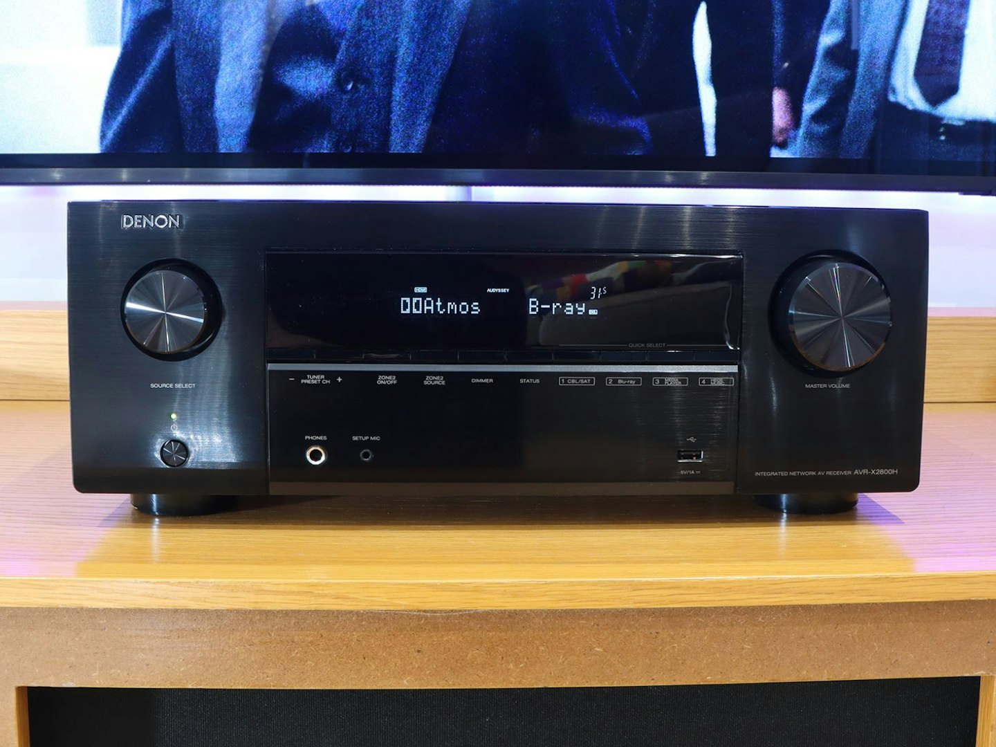 Denon AVR-X2800H Home Cinema Amplifier on a stand in front of a TV