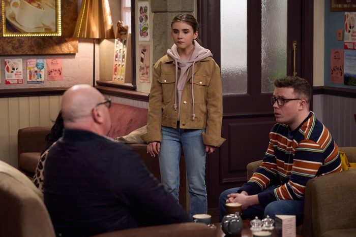 16_04_emm_paddy_april_01 Paddy and Vinny sit in the cafe, with April stood over them in a scene from Emmerdale