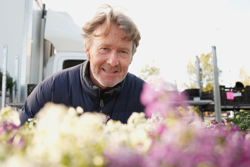 Paul smiles near a bunch of flowers.
