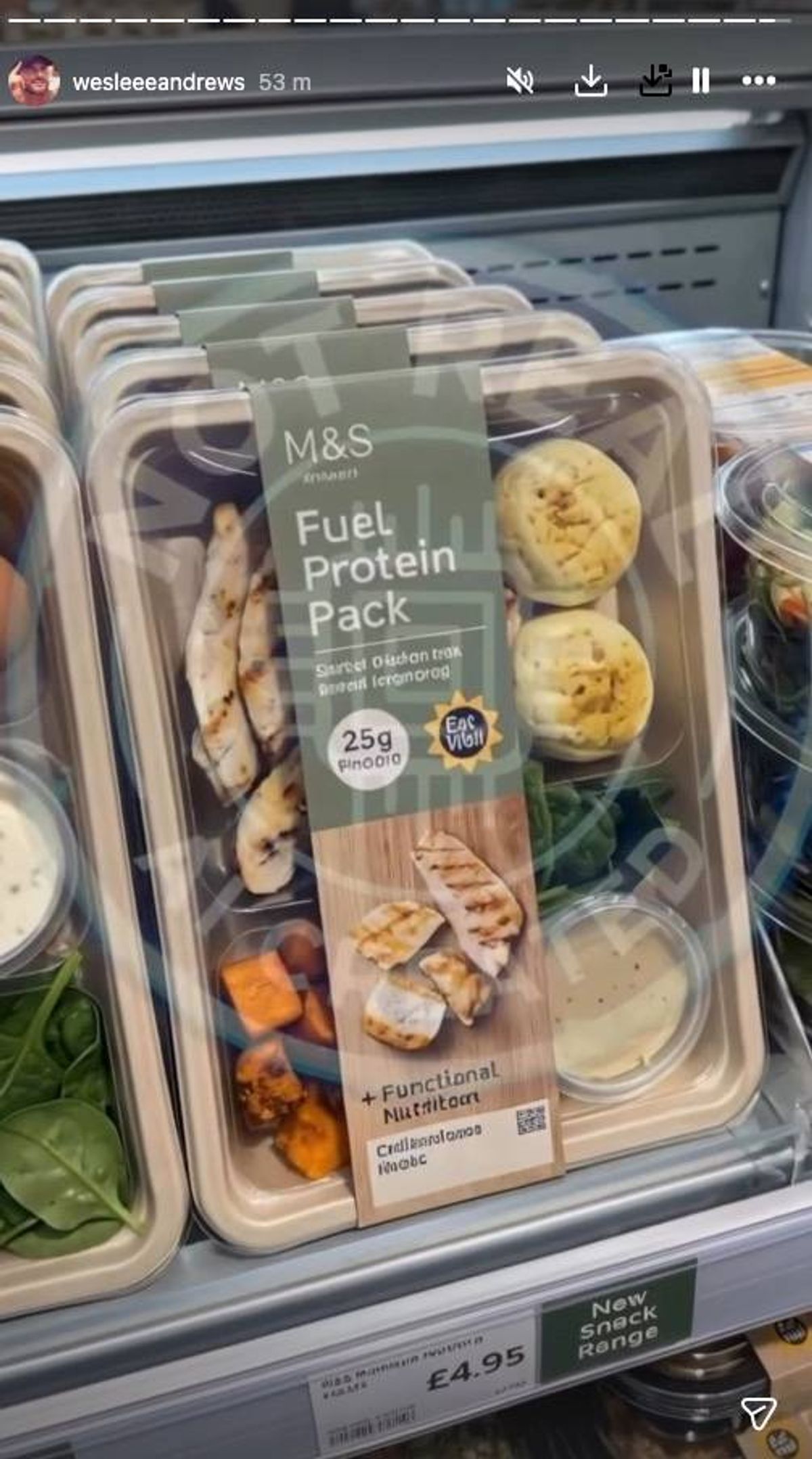 Multiple transparent plastic containers stacked on top of each other, each containing a yellow, bite-sized pastry labeled "M&S Fuel Protein Pack". The containers are sealed and placed on a table.