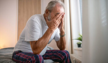 Elderly man with a concerned expression sitting at a desk, symbolizing anxiety and contemplation in aging or financial mat...