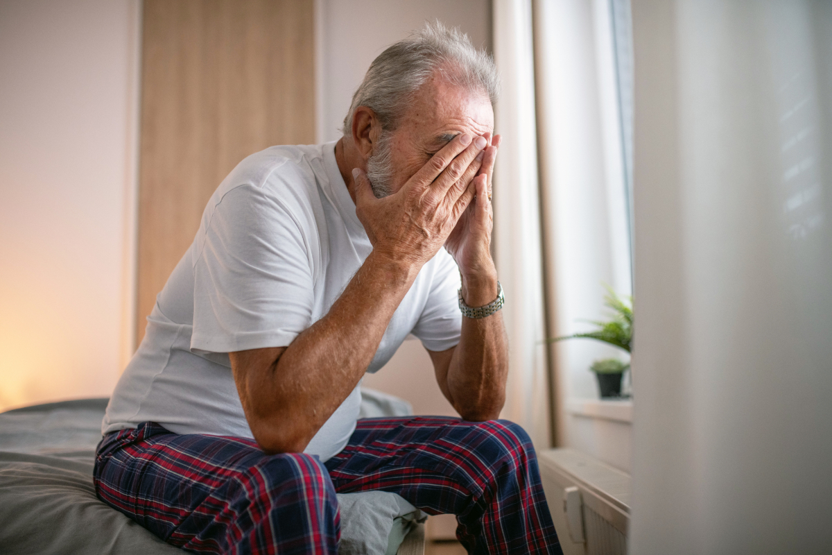 Elderly man with a concerned expression sitting at a desk, symbolizing anxiety and contemplation in aging or financial mat...