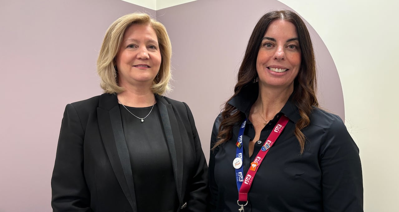 Two women smile at the camera.