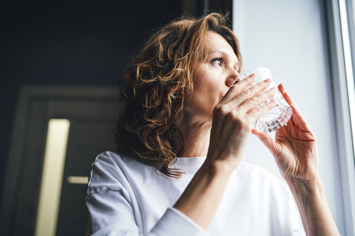 Woman drinking fresh water from a glass, promoting health and wellness