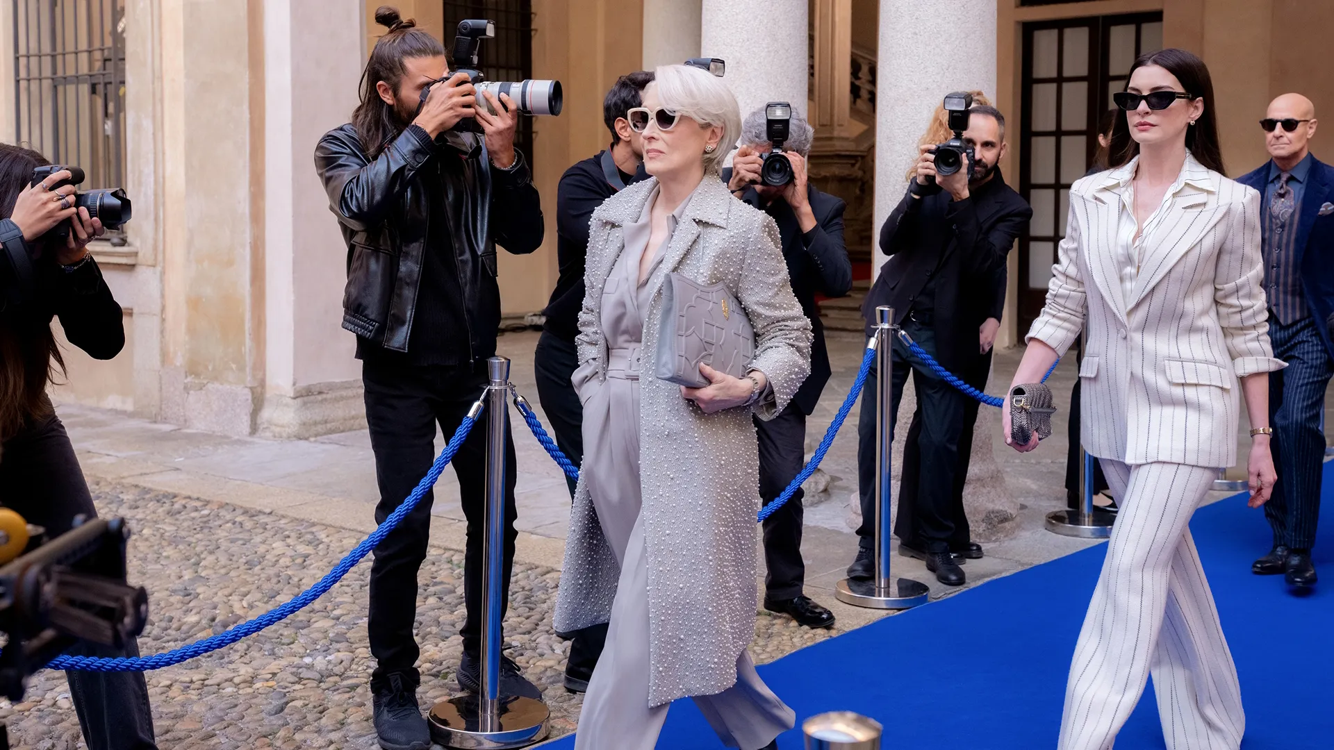Mirana (Meryl Streep) and Andy (Anne Hathaway) walk the carpet as the paparazzi photograph them. 