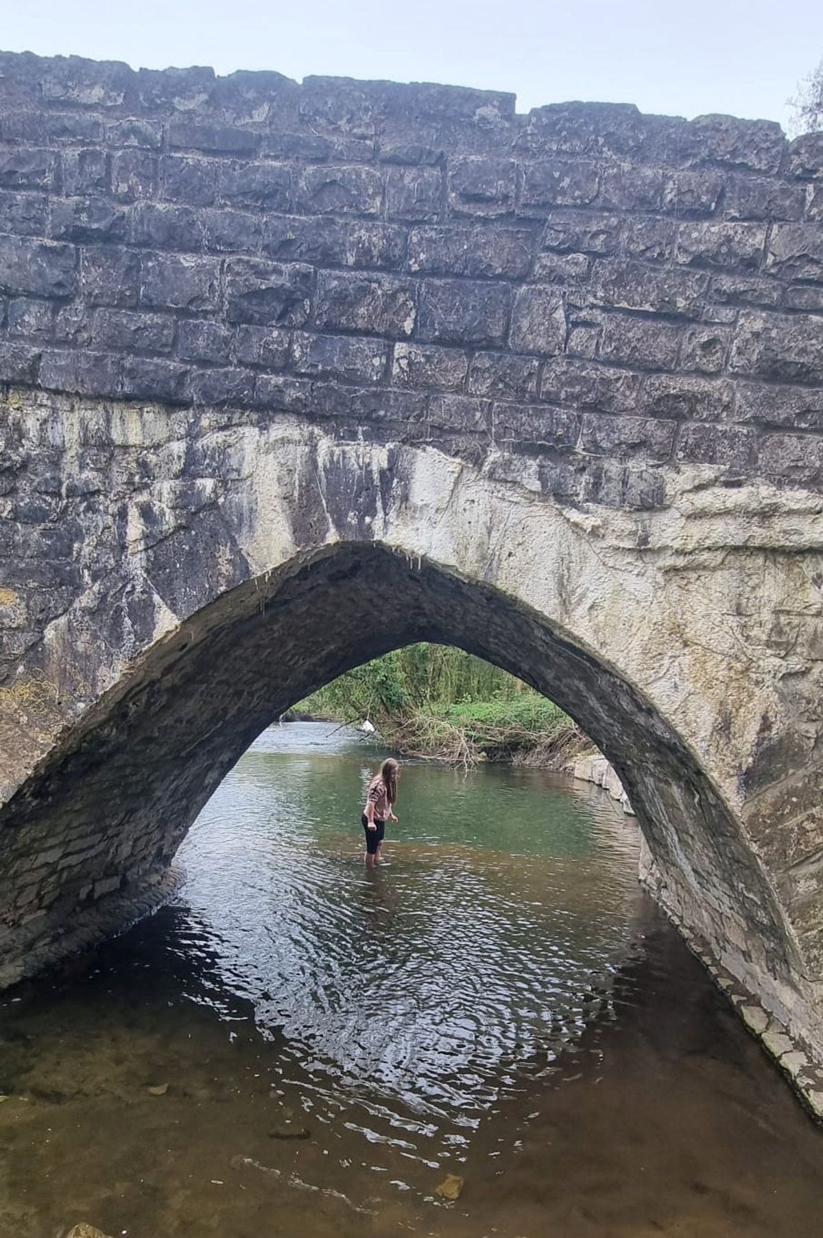 Person stood under bridge in river