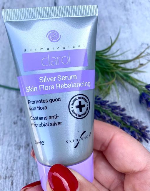 An individual is holding a tube of "Silver Serum Skin Flora Rebalancing" in their hand.