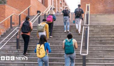 Group of diverse university students walking up outdoor steps, carrying backpacks and heading to classes.