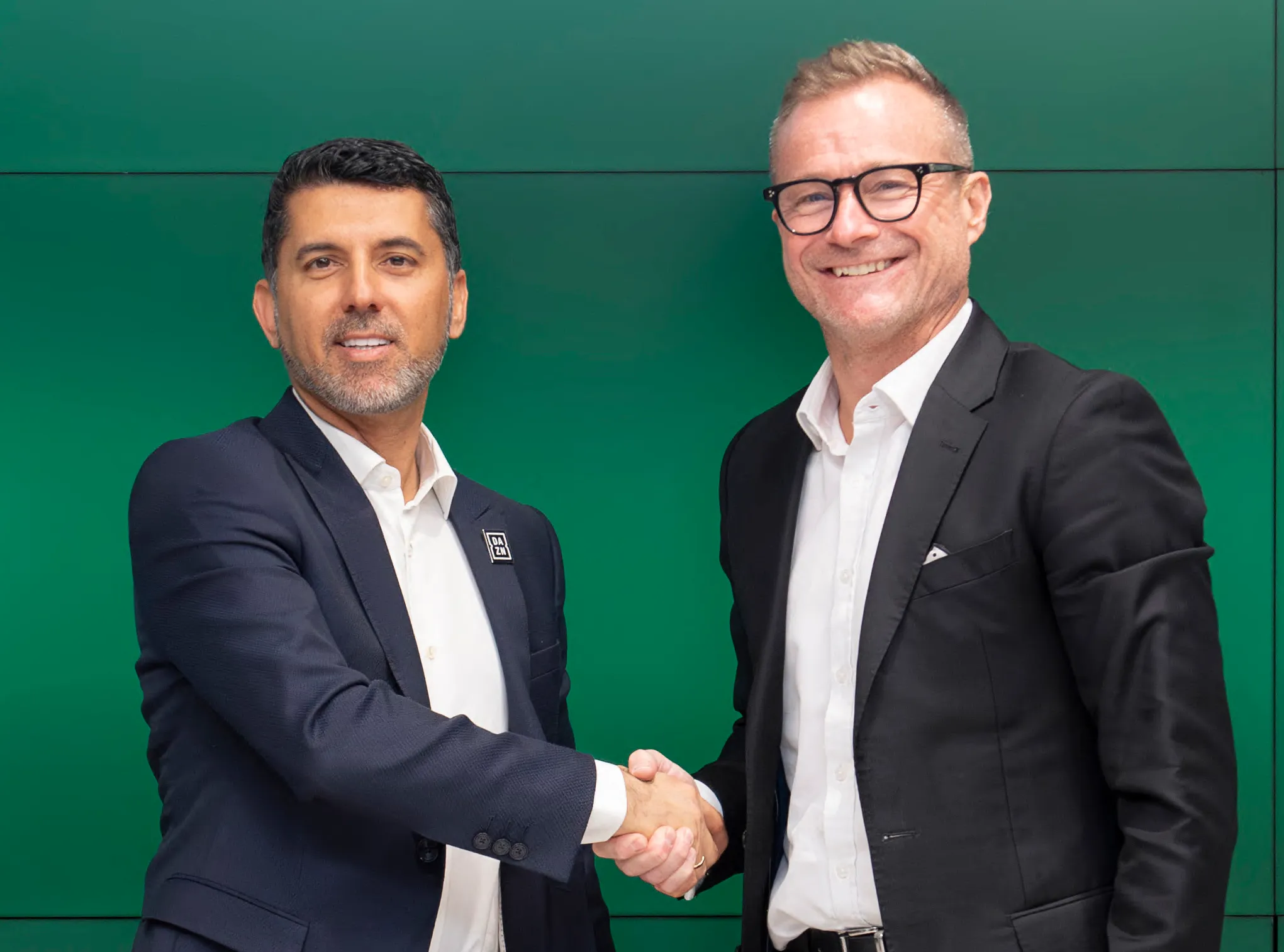 Shay Segev (CEO of DAZN Group) and Danny Townsend (CEO of SURJ Sports Investment) shaking hands.