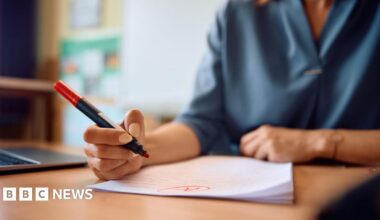 Close up of a teacher reading her pupils' tests in the classroom.