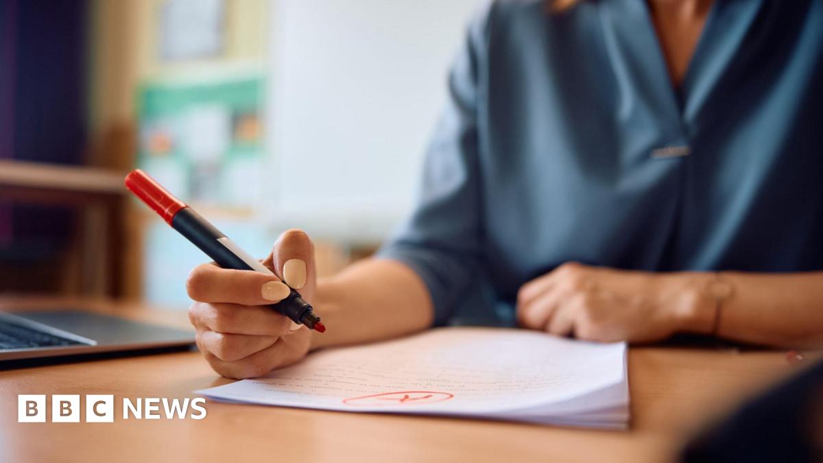Close up of a teacher reading her pupils' tests in the classroom.
