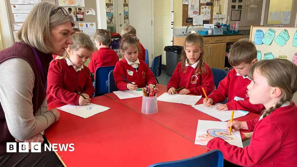 The Duchess of Sussex sitting with a group of young women, gesturing with her hands