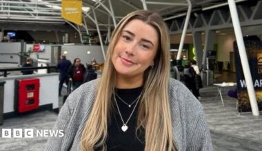 Picture of a white, long haired, blonde, female wearing a grey cardigan with a black top underneath.