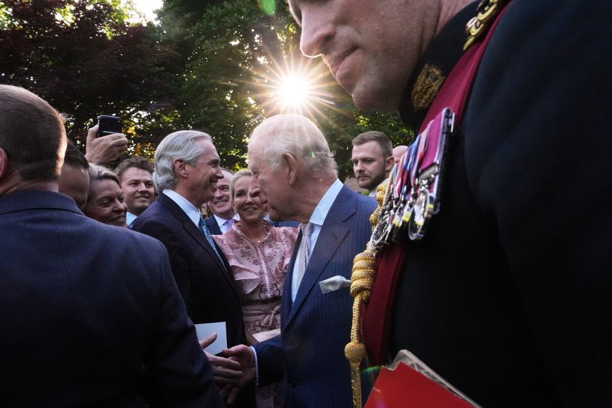 Charles speaks with guests during a garden party at the British Embassy on Monday.
