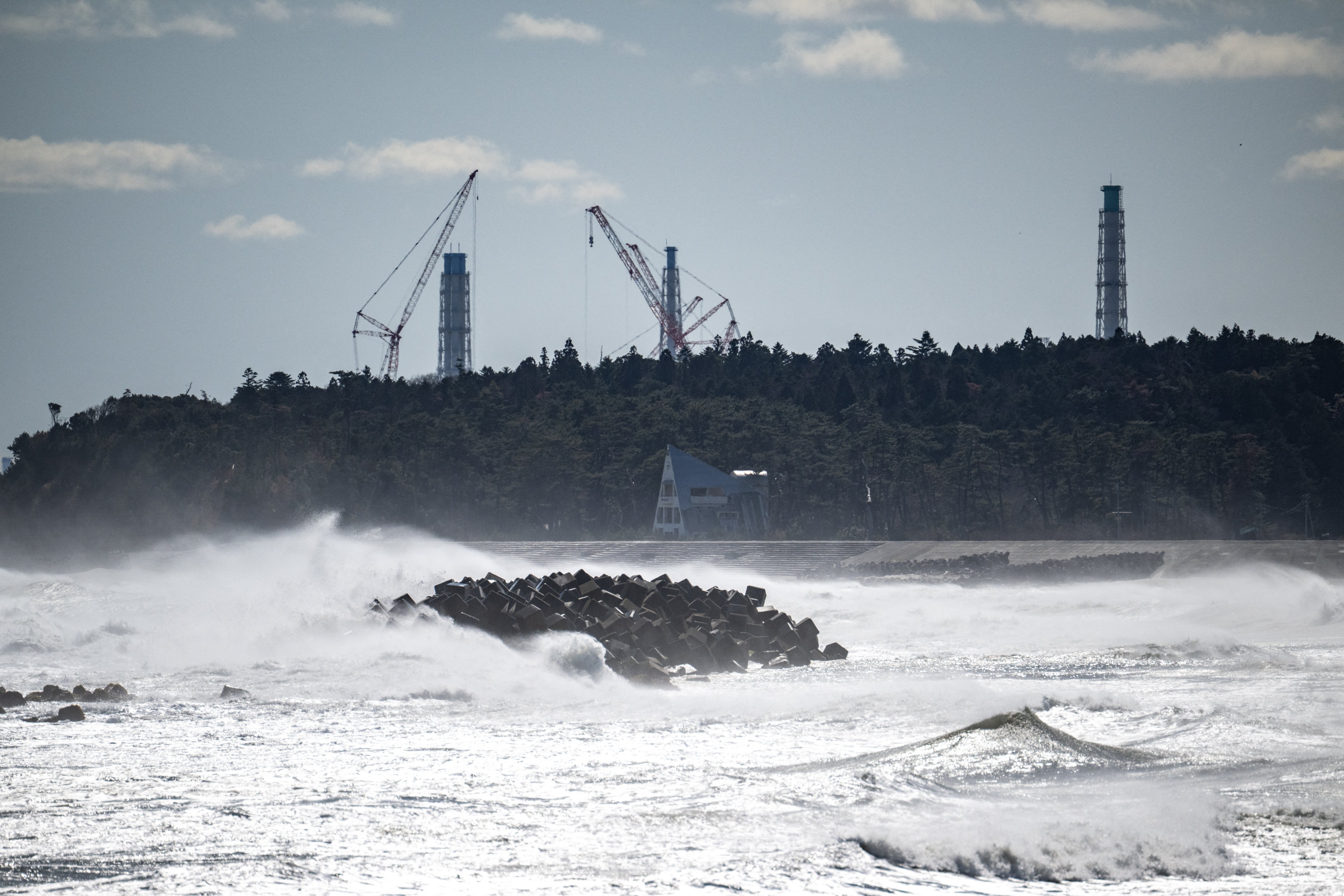 An abandoned building in front of the facilities of the Tokyo Electric Power Company's (TEPCO) Fukushima Daiichi Nuclear Power Plant (back), as seen from Ukedo fishing port in Namie, Fukushima prefecture