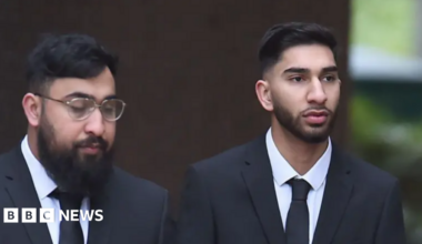 Brothers Muhammad Amaad (left) and Mohammed Fahir Amaaz who have black hair and beards and are wearing black suits with white shirts and ties. Muhammad Amaad wears glasses. The pair are not smiling.