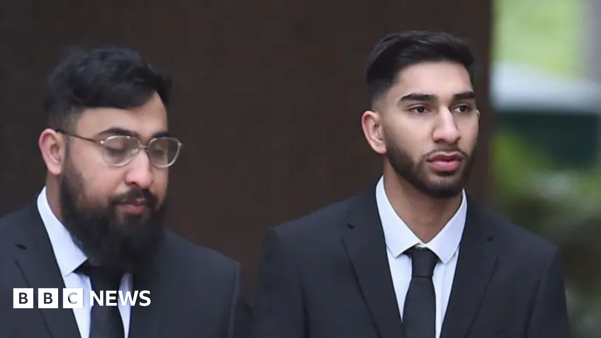 Brothers Muhammad Amaad (left) and Mohammed Fahir Amaaz who have black hair and beards and are wearing black suits with white shirts and ties. Muhammad Amaad wears glasses. The pair are not smiling.