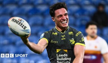 Leeds Rhinos half-back Brodie Croft holds up the ball in one hand and grins to celebrate one of his four tries against Huddersfield Giants