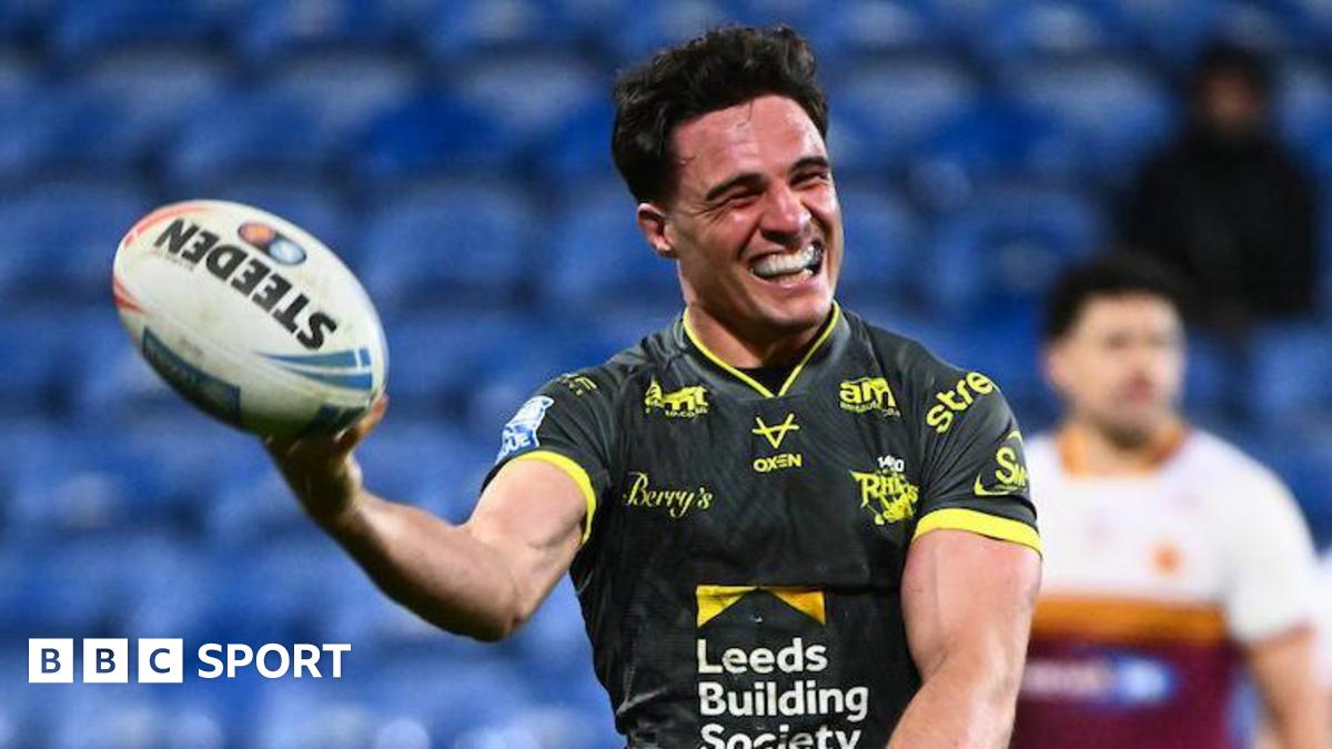Leeds Rhinos half-back Brodie Croft holds up the ball in one hand and grins to celebrate one of his four tries against Huddersfield Giants