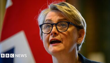 Foreign Secretary Yvette Cooper hosts a virtual meeting at the Foreign, Commonwealth and Development Office (FCDO) in Westminster. She wears black glasses, and a Union Jack is visible behind her.
