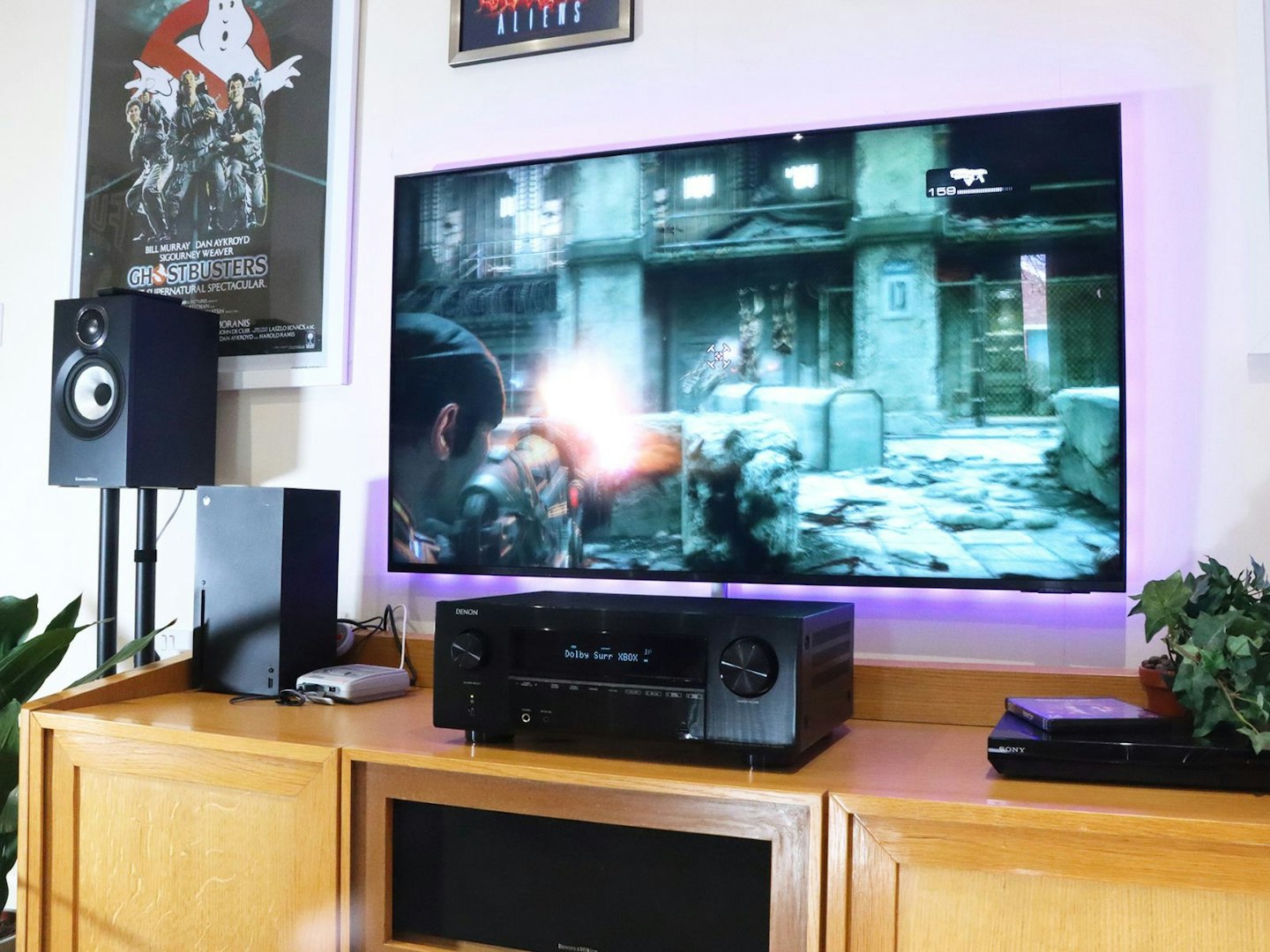 Denon AVR-X2800H Home Cinema Amplifier on a stand in a living room with xbox and snes console in front of a TV showing Gears of War