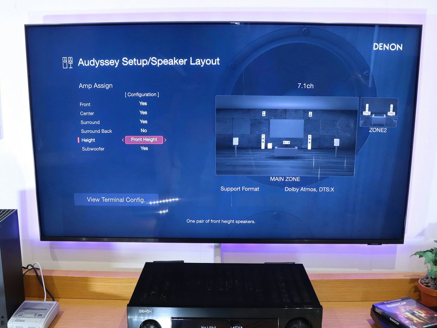 Denon AVR-X2800H Home Cinema Amplifier on a stand in a living room - tv showing audyssey setup menu