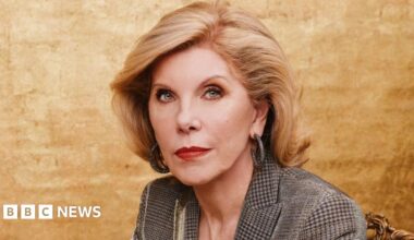 Christine Baranski sitting in front of a gold background