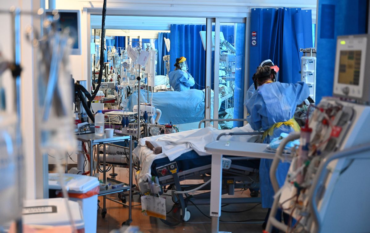 Healthcare workers in PPE standing over the beds of sick patients during the coronavirus pandemic on the Intensive Care Unit at the Royal Papworth Hospital in Cambridge