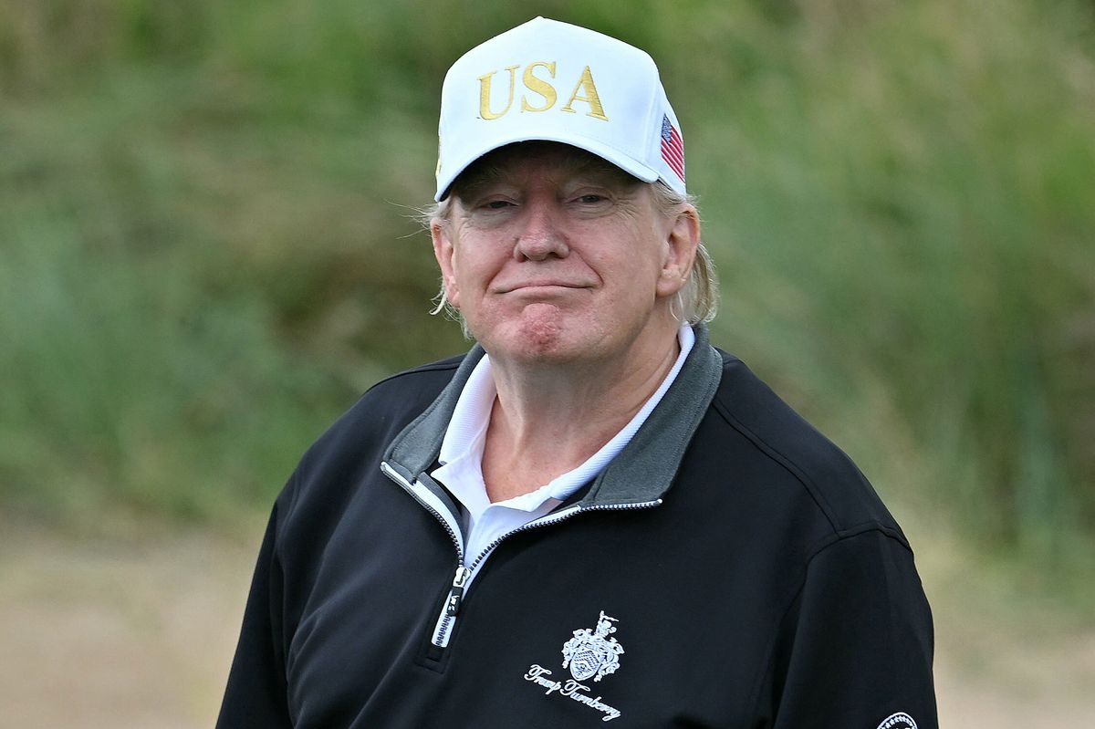 US President Donald Trump reacts after playing from the first tee to officially open the Trump International Golf Links course in Balmedie, Aberdeenshire