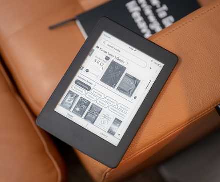 2015 Amazon Kindle Paperwhite eReader sitting on a couch showing the home screen.