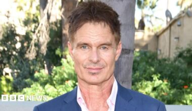 Patrick Muldoon wearing a white open-necked shirt and blue suit jacket