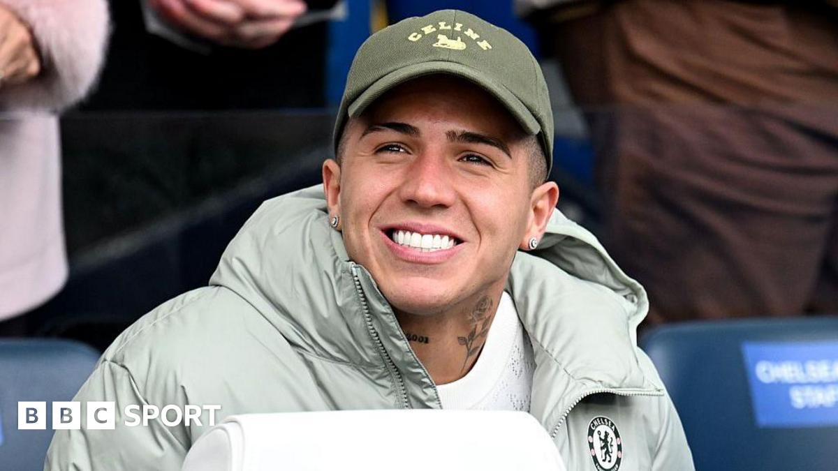Enzo Fernandez smiling while in sat down in a Chelsea jacket