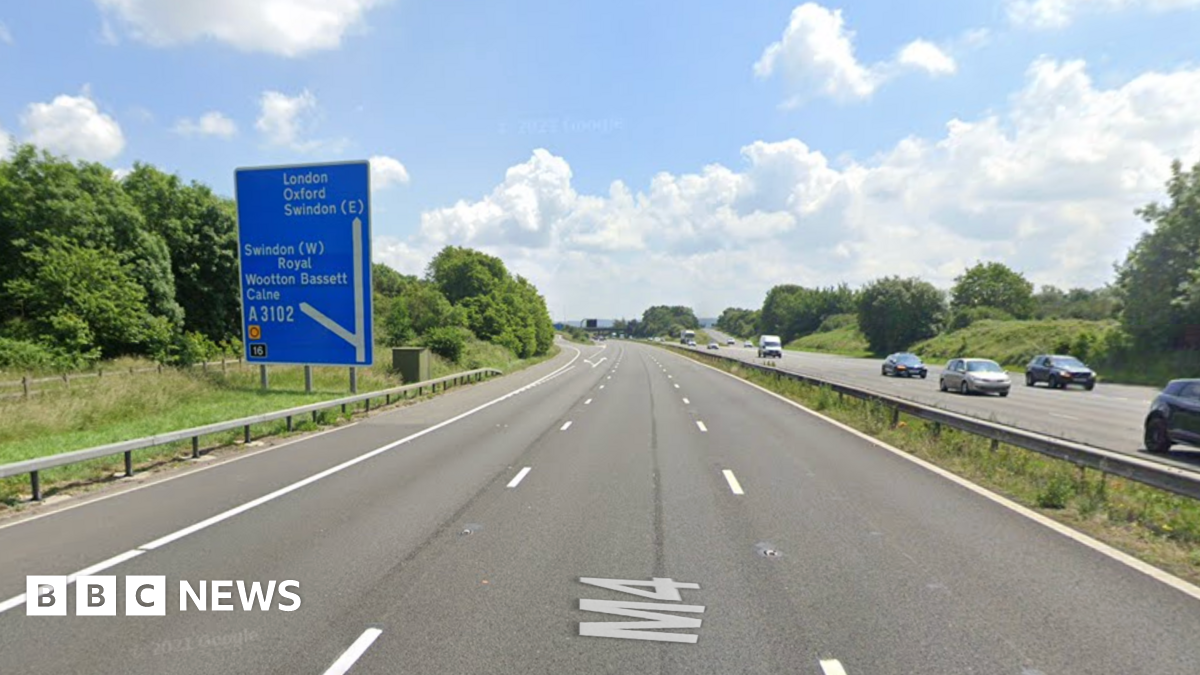 The M4 near Swindon. It has three lanes and there is a blue road sign on the left.
