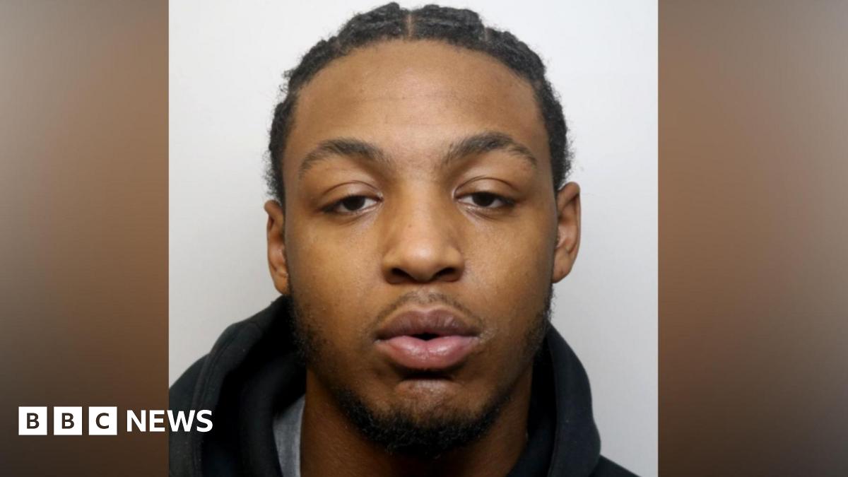 Dino Donaldson, a  young man with a goatee beard, stares into a camera for a police custody photo.
