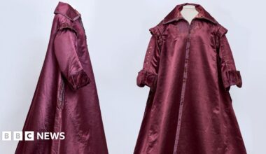 A side and front view of a 1600s era gown. It is a burgundy colour and has a collar.