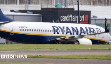 A Ryanair flight parked at Cardiff Airport, with the airport's logo seen in the background.