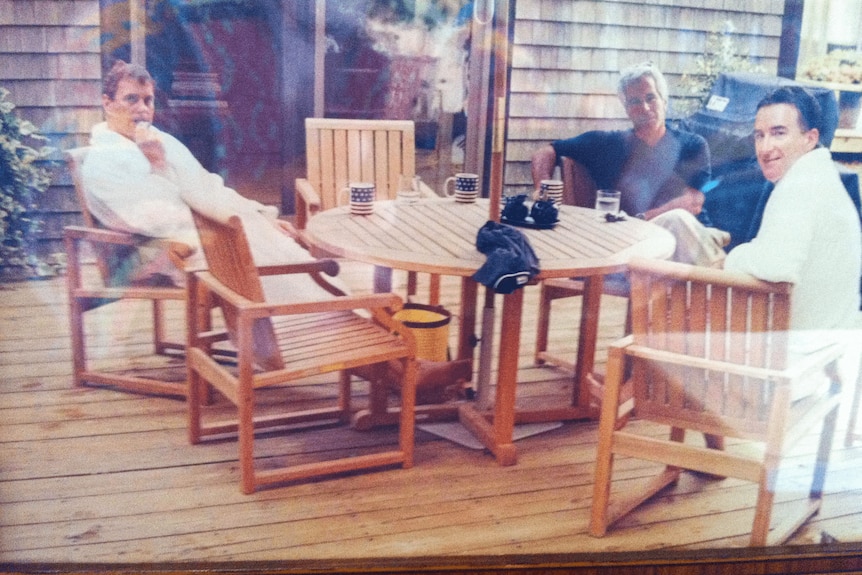 A blurred image of former Prince Andrew Mountbatten-Windsor, Peter Mandelson and Jeffrey Epstein sitting on a verandah.