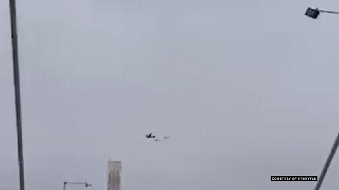 Plane flying through the sky with an object falling from it.