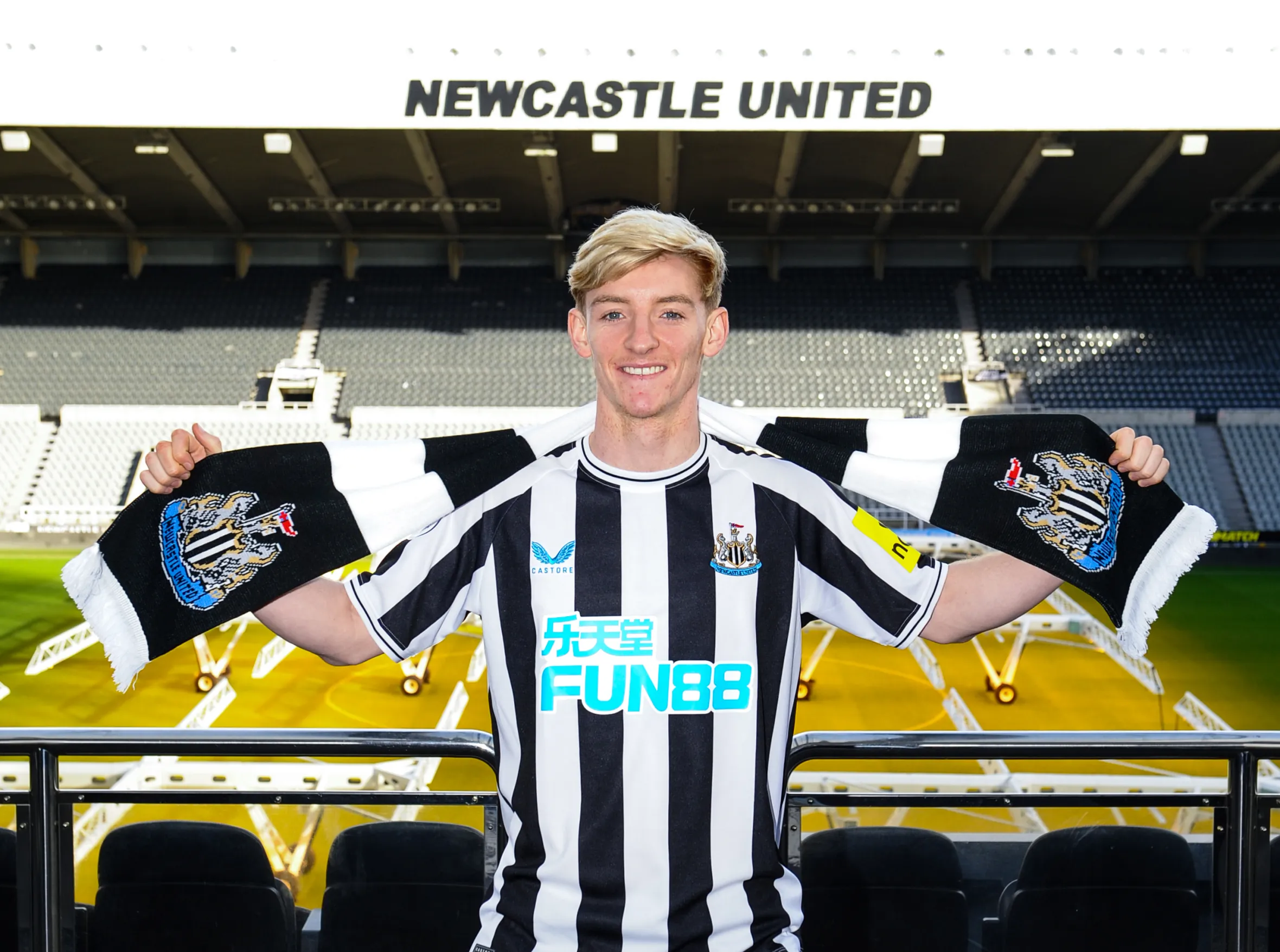 Anthony Gordon poses for photos with a scarf after signing at St. James' Park.