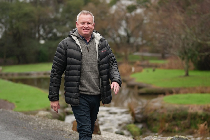A man strolls in a park environment.